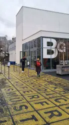 People Walking Down A Sidewalk Near A Building