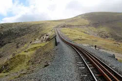Train Traveling Down A Train Track Near A Mountain