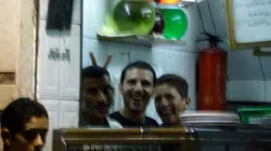 Two Men Are Standing In Front Of A Counter