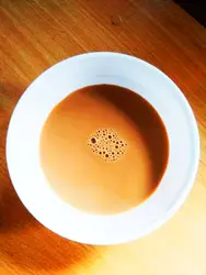 Cup Of Coffee Sitting On A Table Next To A White Plate