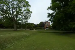 Small House In A Green Field With Trees