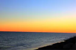 Sunset On A Beach With A View Of The Water