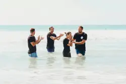 Three Men Are Standing On The Beach With A Frisbee