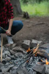 Man Is Cooking A Fire In A Wooded Area