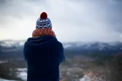 Person Wearing A Hat And Holding A Snowboard
