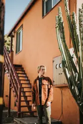 Woman Standing Next To A Building With A Wooden Bench