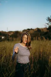Woman Standing In A Field With A Stick In Her Hand