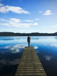 Person Standing On A Dock Near A Body Of Water