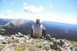 Person Standing On Top Of A Mountain With A Camera