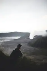 Man Standing In A Field With A Mountain