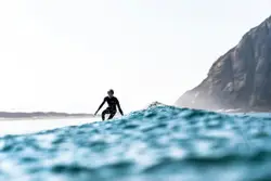 Man Riding A Surfboard On Top Of A Wave