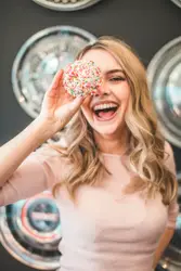 Woman Is Holding A Doughnut Up To Her Face