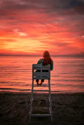 Woman Sitting On A Bench On A Beach