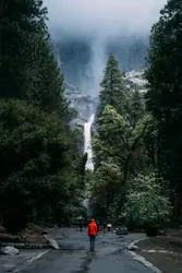 Man Walking Down A Snowy Hill With A Mountain