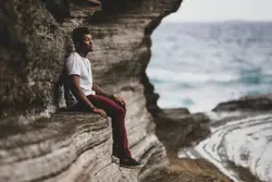 Man Sitting On A Rock Ledge Overlooking A River