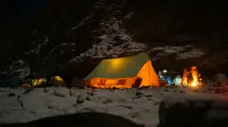 People surrounding bonfire near tent on shore