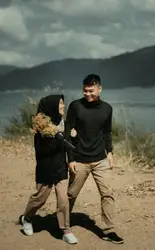 Smiling man and woman walking near bush