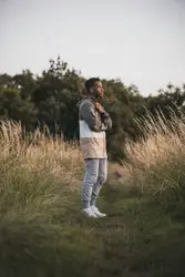Man wearing jacket and pants standing on grass field