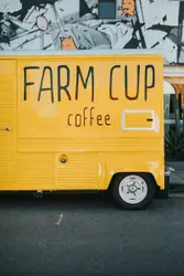 Yellow Farm Cup Coffee truck parked beside sidewalk