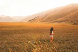 Woman standing on brown grass field