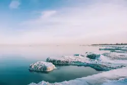 Snowfield near body of water view during daytime