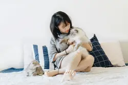 Woman holding cat beside another cat