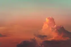 A large cloud is in the sky at sunset