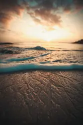 Sea foam on shore during golden hour