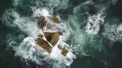 Rock formation surrounded by body of water in aerial ph