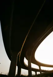 The underside of a highway bridge with a traffic light