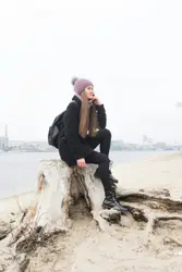 Woman in black jacket standing on rock near sea during 
