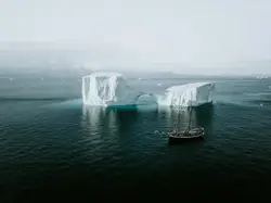Schooner sailing by an iceberg in the Arctic