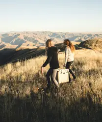Two woman carrying cooler box