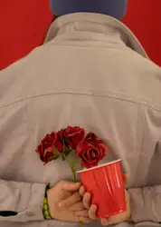 Person holding red mug and red flowers