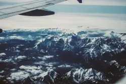 Airplane wing crosses snowy mountains