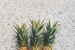 Three yellow pineapple fruits on white surface