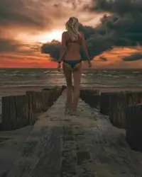 Woman wearing bikini standing on wooden dock