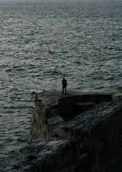 Man standing on cliff near the bodies of water