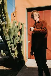 Man wearing brown long sleeved shirt near green plant