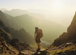 Climber standing on rock near overlooking view of mount