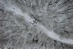 Aerial view of road between trees covered with snow dur