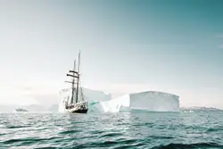 White sailing ship beside iceberg