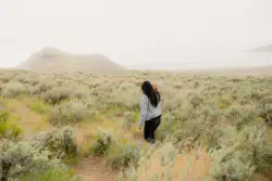 Woman in white long sleeve shirt and black pants standi