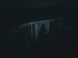 A bridge at night with cars driving.