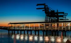 Black wooden dock on body of water during sunset