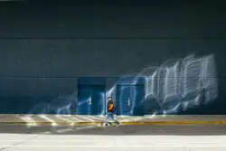 Person walks past doors in the sunlight.