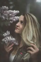 Woman in grey jacket holding purple hydrangeas