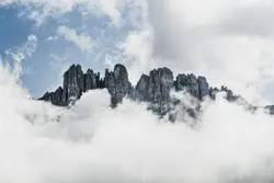 A mountain covered in clouds under a blue sky