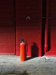 Red fire extinguisher near red wall