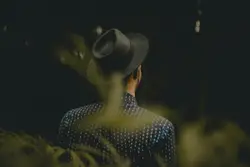 Woman wearing fedora hat facing the forest